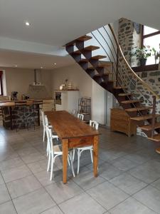 uma sala de jantar com uma mesa de madeira e uma escada em La Maison de Lili em Loudes