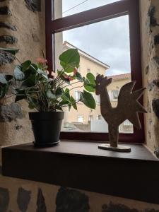 a window sill with a potted plant and a cat statue at La Maison de Lili in Loudes