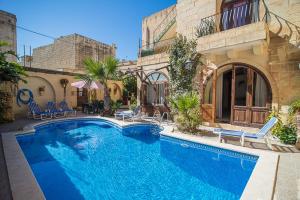 a swimming pool in front of a house at 4 Bedroom Farmhouse with Large Private Pool in Żebbuġ