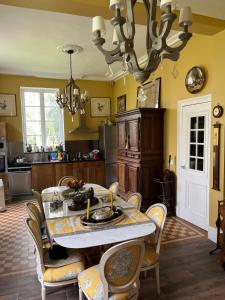 een keuken met een tafel met stoelen en een kroonluchter bij Chateau de Saint Aubin in Thiberville