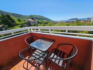 2 Stühle und ein Tisch auf einem Balkon mit Bergblick in der Unterkunft Dom M Apartments in Budva