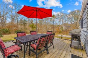 a table and chairs with a red umbrella on a deck at Cozy Large Home in Harwich with Patio near Wequassett Resort in Harwich