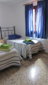 twee bedden in een kamer met blauwe gordijnen bij Villa en Sa Roca in Es Mercadal