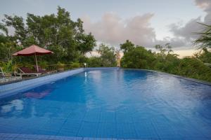 a large blue swimming pool with an umbrella at Innora Jungle Resort And Spa in Nusa Penida