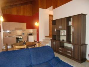 ein Wohnzimmer mit einem blauen Sofa und einer Küche in der Unterkunft Ferienwohnung in Val Maria-Pur mit Großem Balkon und Seeblick in Pieve Di Ledro