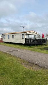 a white house with a porch on the side of a road at Caravan home Clacton-On-Sea St Osyth in Saint Osyth