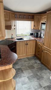 a kitchen with wooden cabinets and a tile floor at Caravan home Clacton-On-Sea St Osyth in Saint Osyth