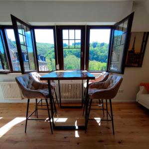 une table et des chaises dans une pièce avec fenêtres dans l'établissement Villa Schöneck Bad Münster, à Bad Kreuznach