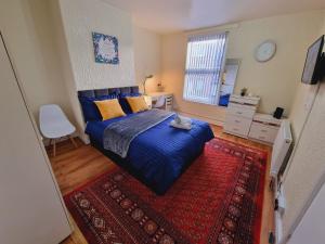 a bedroom with a blue bed and a red rug at Bright sunny, double bed with garden, TV and Wi-Fi in Leeds