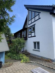 溫特貝格的住宿－Landhaus am Bach in Winterberg-Silbach，白色的房子,设有黑窗和庭院