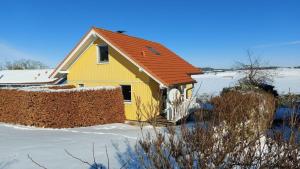 une maison jaune avec un toit rouge dans la neige dans l'établissement Das magische Geschichtenhaus - Einfach wohlfühlen in der Holsteinischen Schweiz, à Schönwalde am Bungsberg