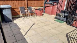 two chairs sitting on a patio next to a fence at Bright sunny, double bed with garden, TV and Wi-Fi in Leeds