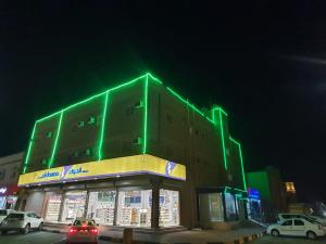 um edifício com luzes verdes em cima em العييري للشقق المفروشة االنعيريه 1 em Al Nairyah
