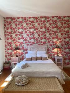1 dormitorio con 1 cama grande y pared de flores en La Maison Reverdi, en Lamarque
