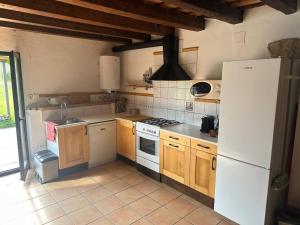 a kitchen with wooden cabinets and a white refrigerator at Mas La Cassanya in Terrades