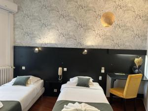 a room with two beds and a table and a chair at Hôtel Abalone - Centre Gare in Nîmes