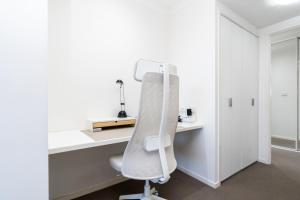 a white office with a chair and a desk at Spacious and Cosy Apt with Great Views in Braddon - Hosted by CanStay in Canberra