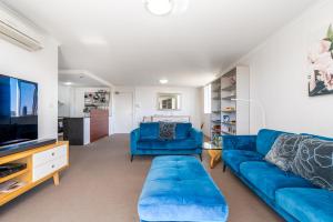 a living room with a blue couch and a tv at Spacious and Cosy Apt with Great Views in Braddon - Hosted by CanStay in Canberra