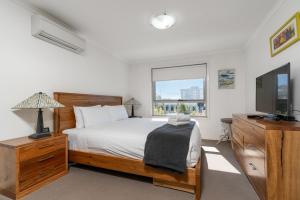 a bedroom with a bed and a television and a window at Spacious and Cosy Apt with Great Views in Braddon - Hosted by CanStay in Canberra