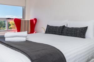 a white bed with black and white pillows and a window at Spacious and Cosy Apt with Great Views in Braddon - Hosted by CanStay in Canberra +10 photos