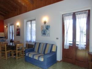 een woonkamer met een blauwe stoel en een tafel bij Appartement in Val Maria-Pur mit Großem Balkon und Seeblick in Pieve Di Ledro