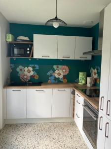 a kitchen with white cabinets and a green wall at Vacances au calme aux 3 Bouchots in Quend