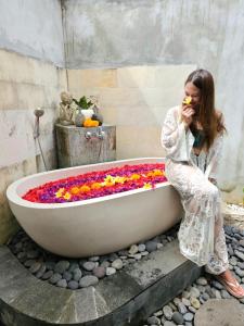 Eine Frau, die in einer Badewanne mit Blumen sitzt. in der Unterkunft Innora Jungle Resort And Spa in Nusa Penida