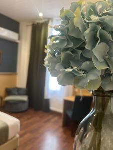 a vase with a bouquet of flowers in a living room at Hôtel Abalone - Centre Gare in Nîmes