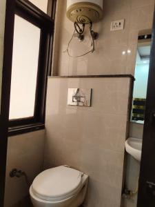 ein Bad mit einem WC, einem Fenster und einem Waschbecken in der Unterkunft Hotel Living Rooms- BY Hotel Green Snapper in Neu-Delhi