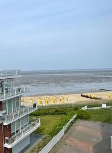 Blick auf einen Strand mit einem Gebäude und das Meer in der Unterkunft Traumhafte Ferienwohnung - direkter Meerblick - 50m zum Strand in Cuxhaven Duhnen in 1A Lage im Haus Seehütte in Cuxhaven