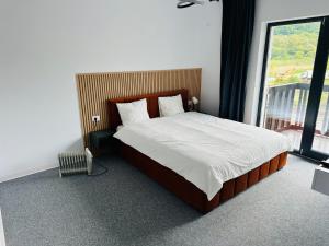 a bedroom with a bed and a large window at GRAND Caciulata in Caciulata