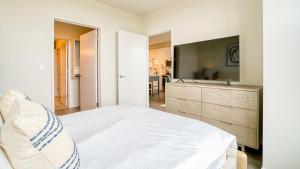 um quarto branco com uma cama grande e uma televisão em Landing at Logan Apartments - 1 Bedroom in Logan Square em Chicago