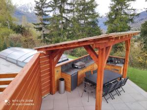 une terrasse en bois avec un grill, une table et des chaises dans l'établissement Laltizoard, à Briançon