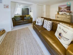 ein Wohnzimmer mit einem braunen Ledersofa in der Unterkunft Peacehaven Cottage - Sidmouth in Sidbury