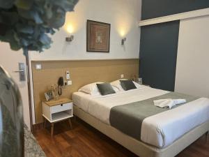 - une chambre avec un grand lit et une table de nuit dans l'établissement Hôtel Abalone - Centre Gare, à Nîmes