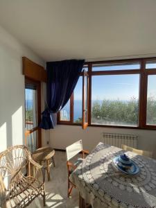 a dining room with a table and chairs and windows at La Villa del Pixus in Pisciotta