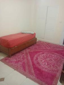 a bedroom with a red bed and a pink rug at Bab ezzouar in Bab Ezzouar