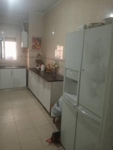 a kitchen with white cabinets and a white refrigerator at Bab ezzouar in Bab Ezzouar