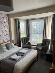 a hotel room with a bed and two chairs at Willows Guest House in Great Yarmouth