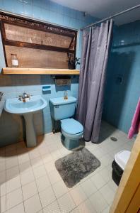 a blue bathroom with a toilet and a sink at La Embajada Hostel in San Cristóbal de Las Casas