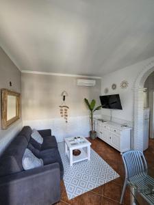 sala de estar con sofá y TV en Pedregalejo Beach House, en Málaga