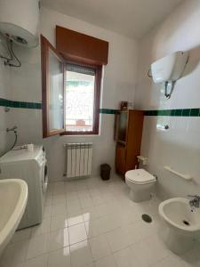 a bathroom with a sink and a toilet and a window at La Villa del Pixus in Pisciotta