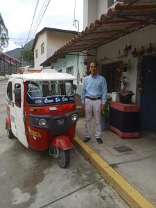 un hombre está parado junto a un pequeño vehículo en Hospedaje Quillabamba en Santa Teresa