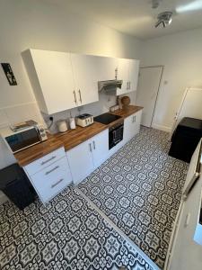 a kitchen with white cabinets and a tile floor at 3-Bed House, Birmingham in Birmingham