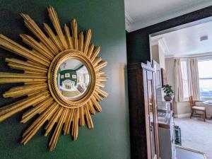 a gold sunburst mirror on a green wall at Deco Studio: King bed, kitchenette, stylish & comfortable in Brighton & Hove