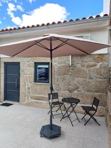 una mesa y dos sillas bajo una sombrilla en un patio en Casa da Póvoa, en Seia