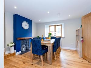 una sala da pranzo con parete blu e tavolo e sedie di 5 Bedroom Cottage - Somerset Pass the Keys a Shapwick