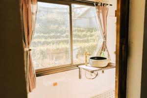 - une fenêtre dans une salle de bains avec un bol sur une étagère dans l'établissement Plum Eco House, à Sa Pa