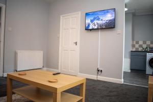 a room with a table and a television on the wall at Stylish 1 Bedroom Flat Newcastle in Old Walker