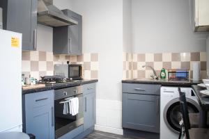 a kitchen with blue cabinets and a washing machine at Stylish 1 Bedroom Flat Newcastle in Old Walker
